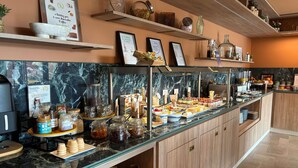 Een buffet met diverse soorten eten, een koffieapparaat en een bord met Novotel erop.