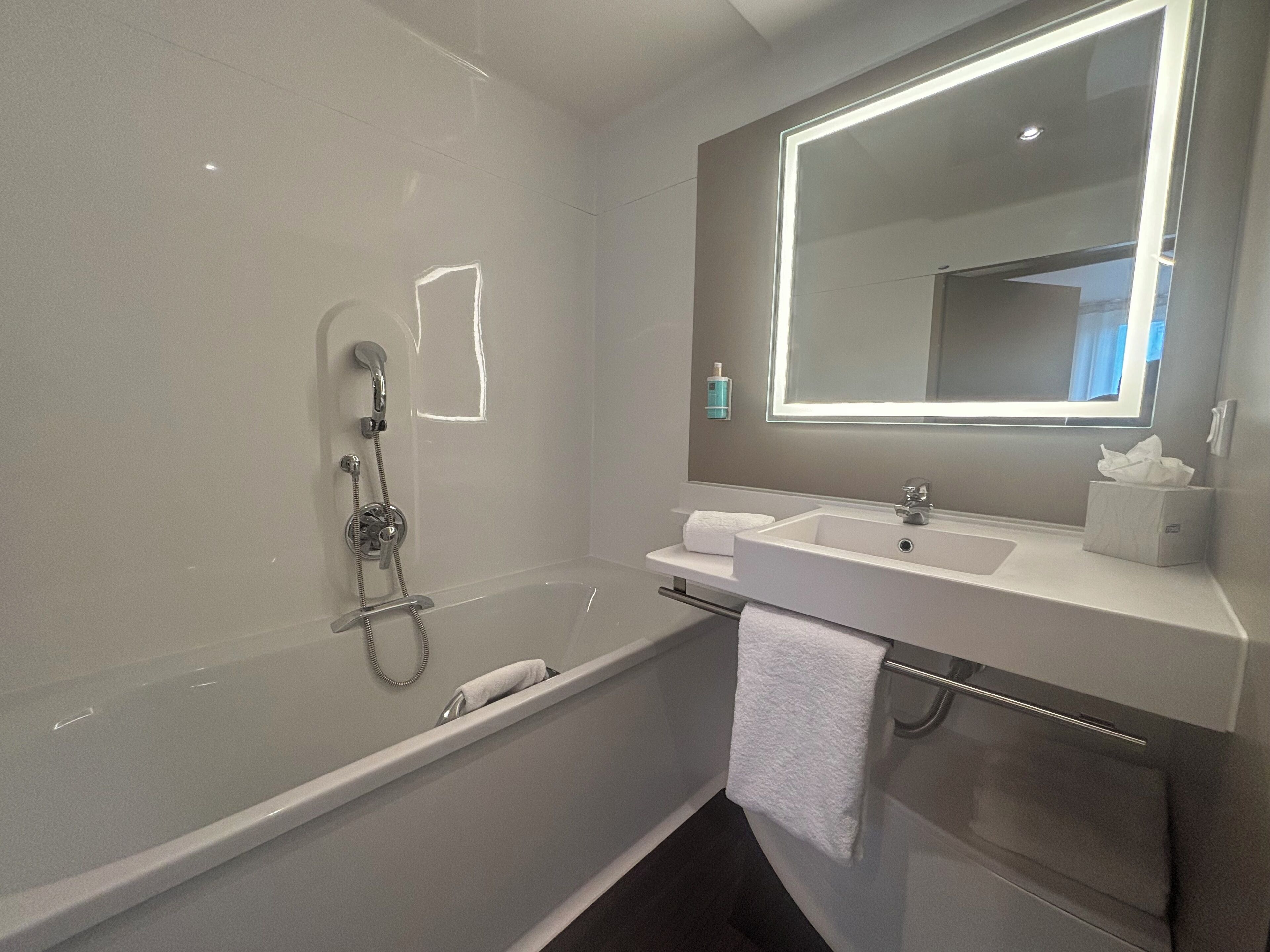 A modern bathroom with a bathtub, a sink, and a large mirror.