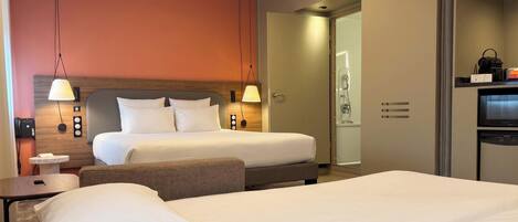 A hotel room with a large bed, bedside tables, a desk, a shower, and a television.