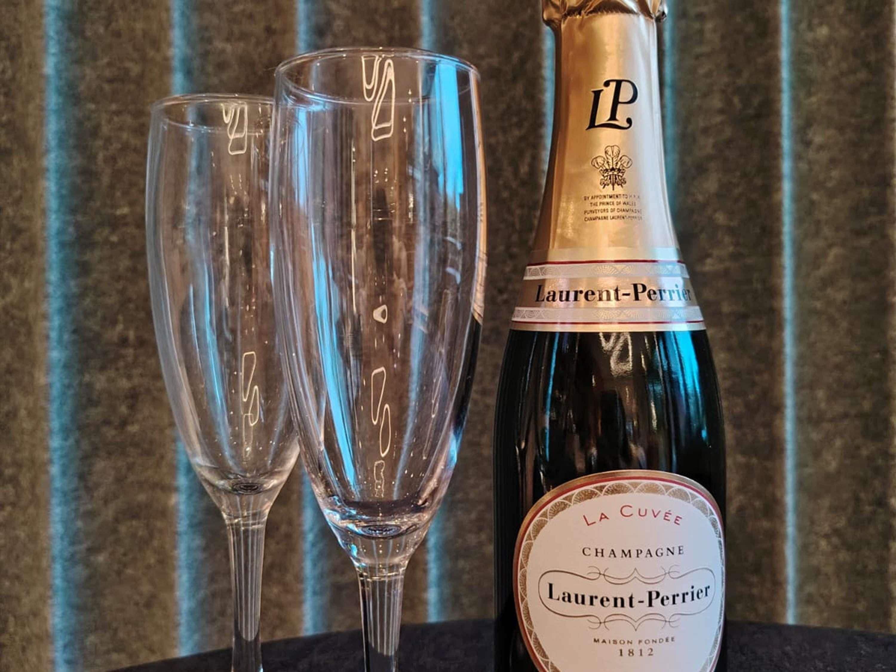 Une bouteille de champagne La Cuvée et deux verres vides.