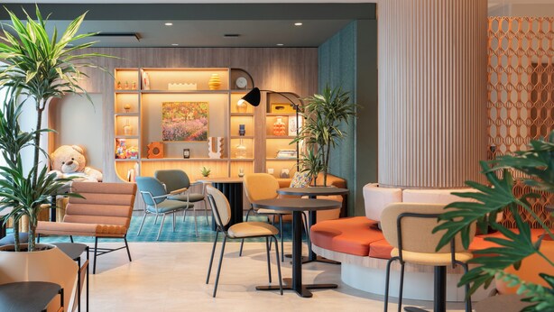 Een modern interieur met een bank, stoelen, een tafel en een boekenplank.