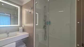 A modern bathroom with a glass shower enclosure, a sink with a mirror, and a towel rack.