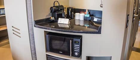 A compact kitchenette with a microwave, a coffee maker, and a small trash bin.