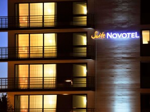A multi-story hotel with illuminated windows and a neon sign reading 'Suite Novotel.' - Novotel Suites Rouen Normandie (Rouen)