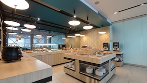 A modern buffet setup with multiple serving stations, a large pot on the left, and a variety of food items displayed. - Hotel Kornati Biograd (Biograd na Moru)