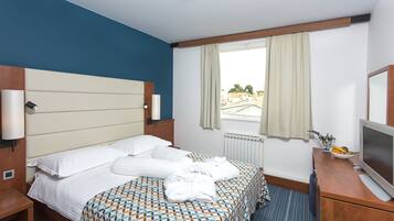 Een hotelkamer met een bed, een bureau met een televisie en een raam met gordijnen.