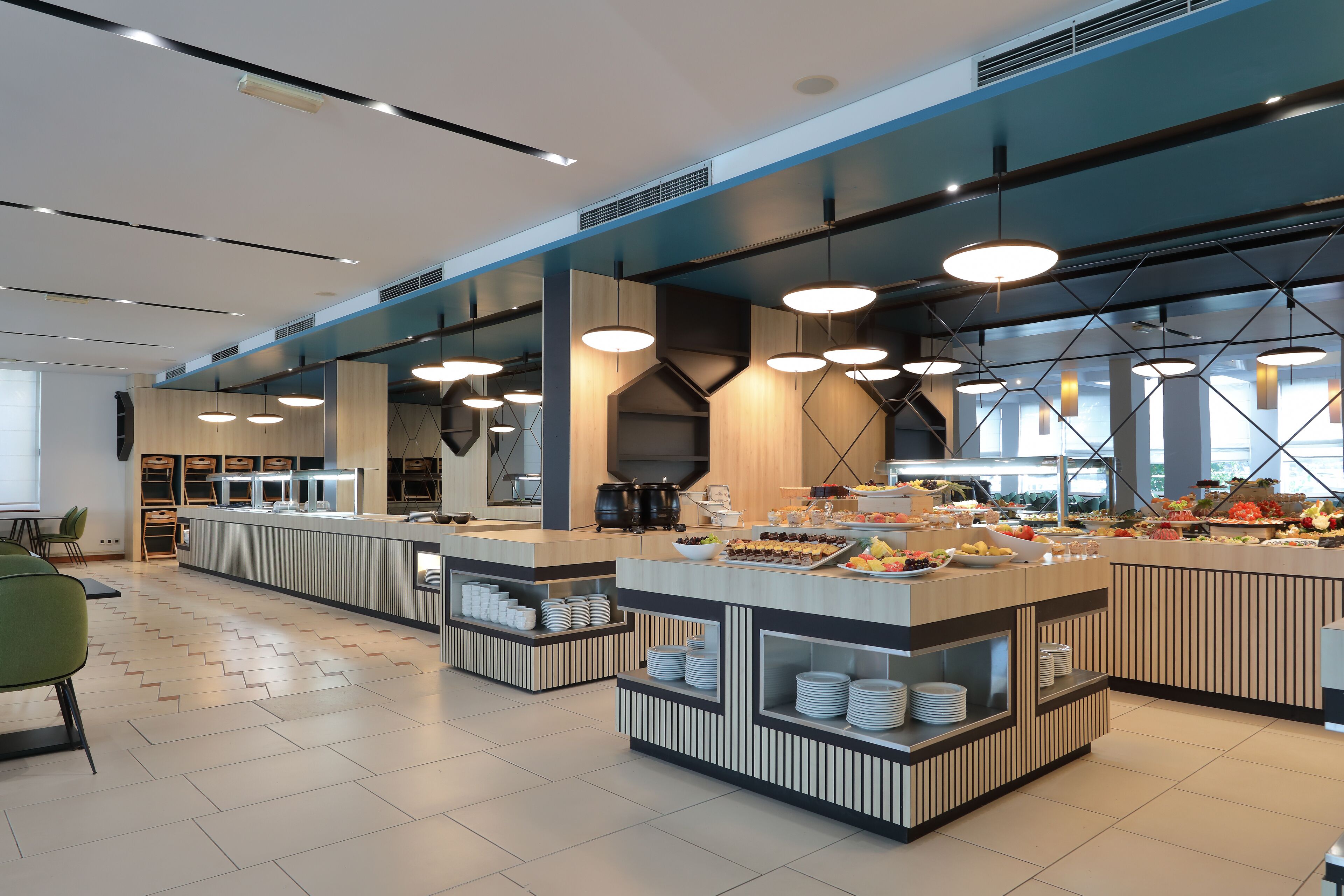 A modern buffet setup with multiple serving stations, a clean tiled floor, and contemporary lighting fixtures.