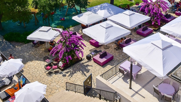 An outdoor seating area with umbrellas, lounge chairs, and a view of the sea. - Hotel Kornati Biograd (Biograd na Moru)