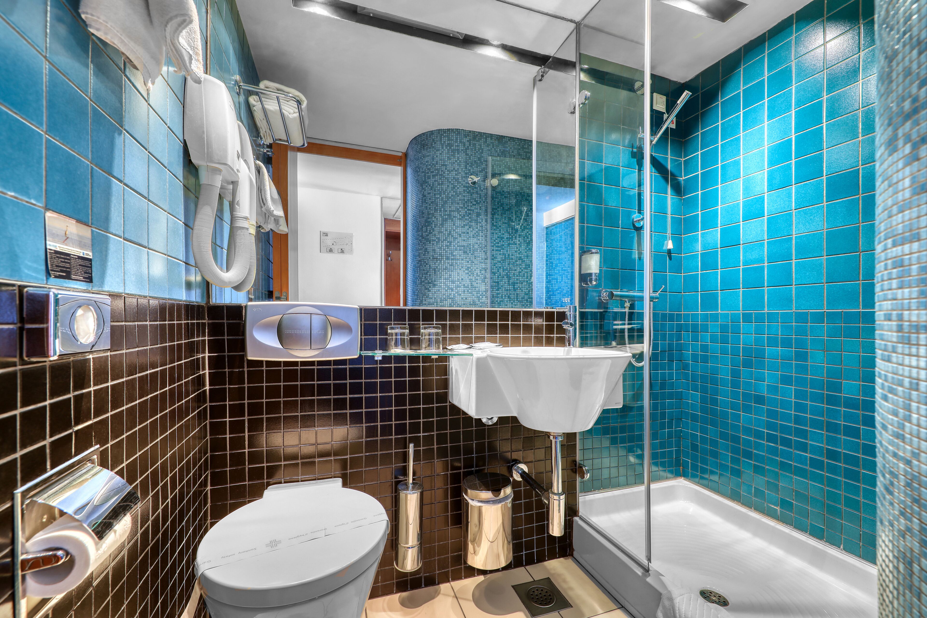 Ein modernes Badezimmer mit Toilette in Weiß, einer Duschkabine aus Glas und einem Waschbecken mit weißer Arbeitsplatte.