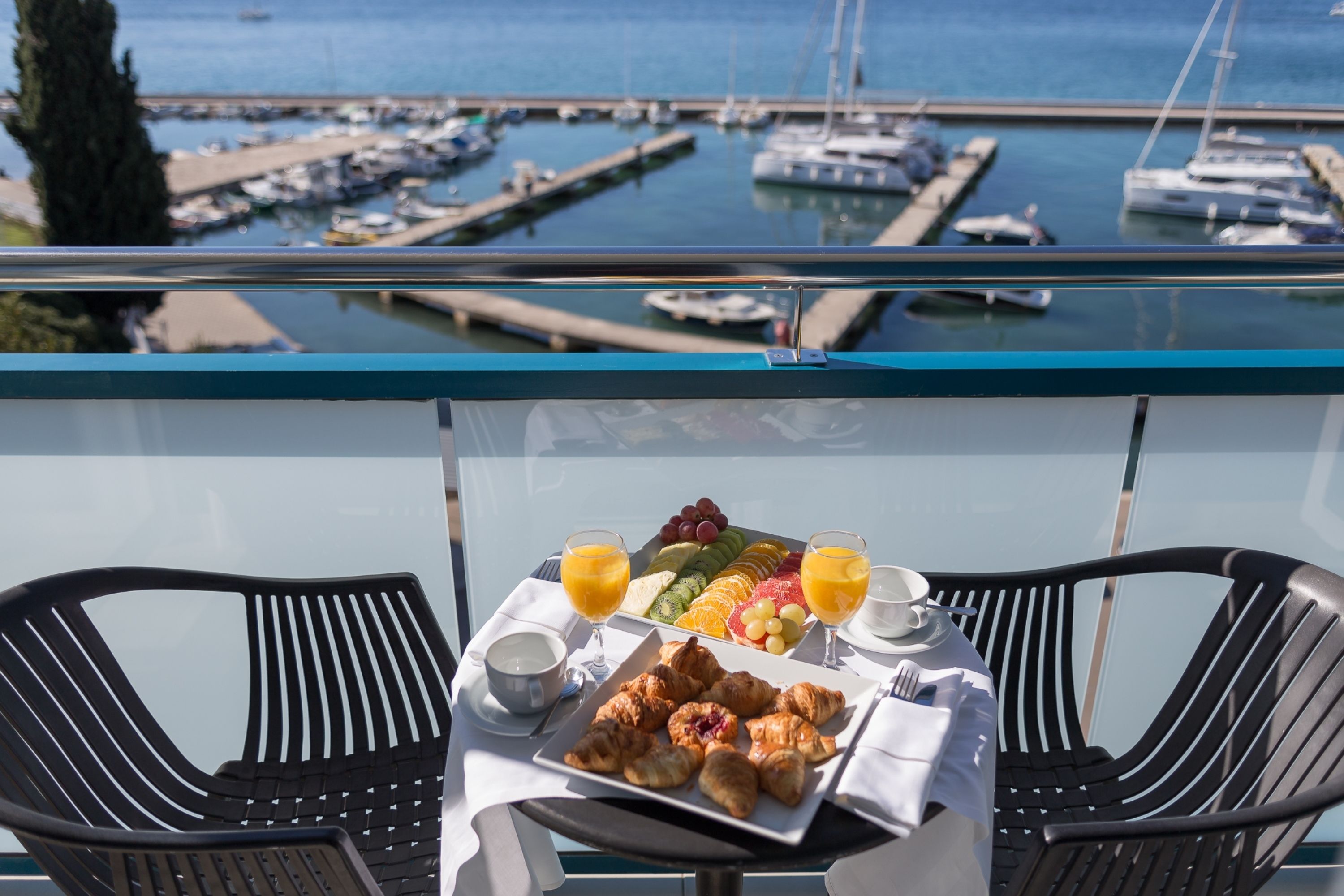 Un balcon avec une table préparée pour le petit-déjeuner, donnant sur une marina où sont amarrés des bateaux.