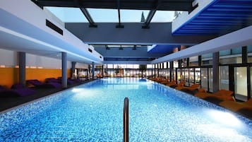 Una piscina techada, una piscina al aire libre de temporada, sombrillas