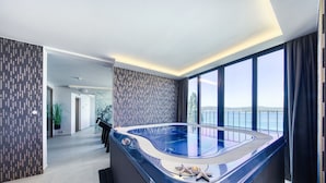 Un baño moderno con una bañera grande, vistas al mar y un papel pintado decorativo.