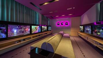 A modern living room with a large flat-screen TV, a sofa, and a gaming console.