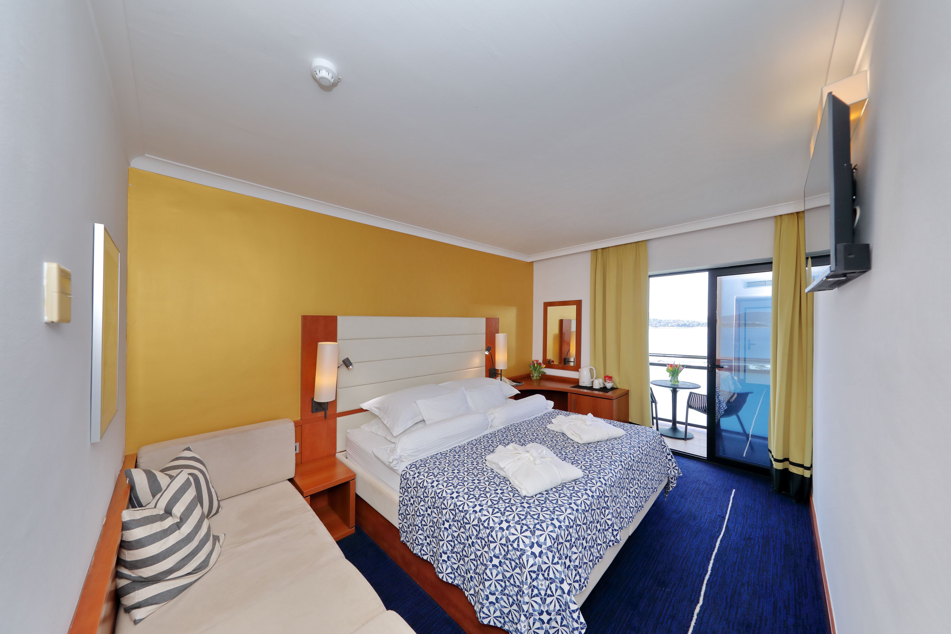 Una habitación de hotel con cama, sofá, escritorio y televisión.