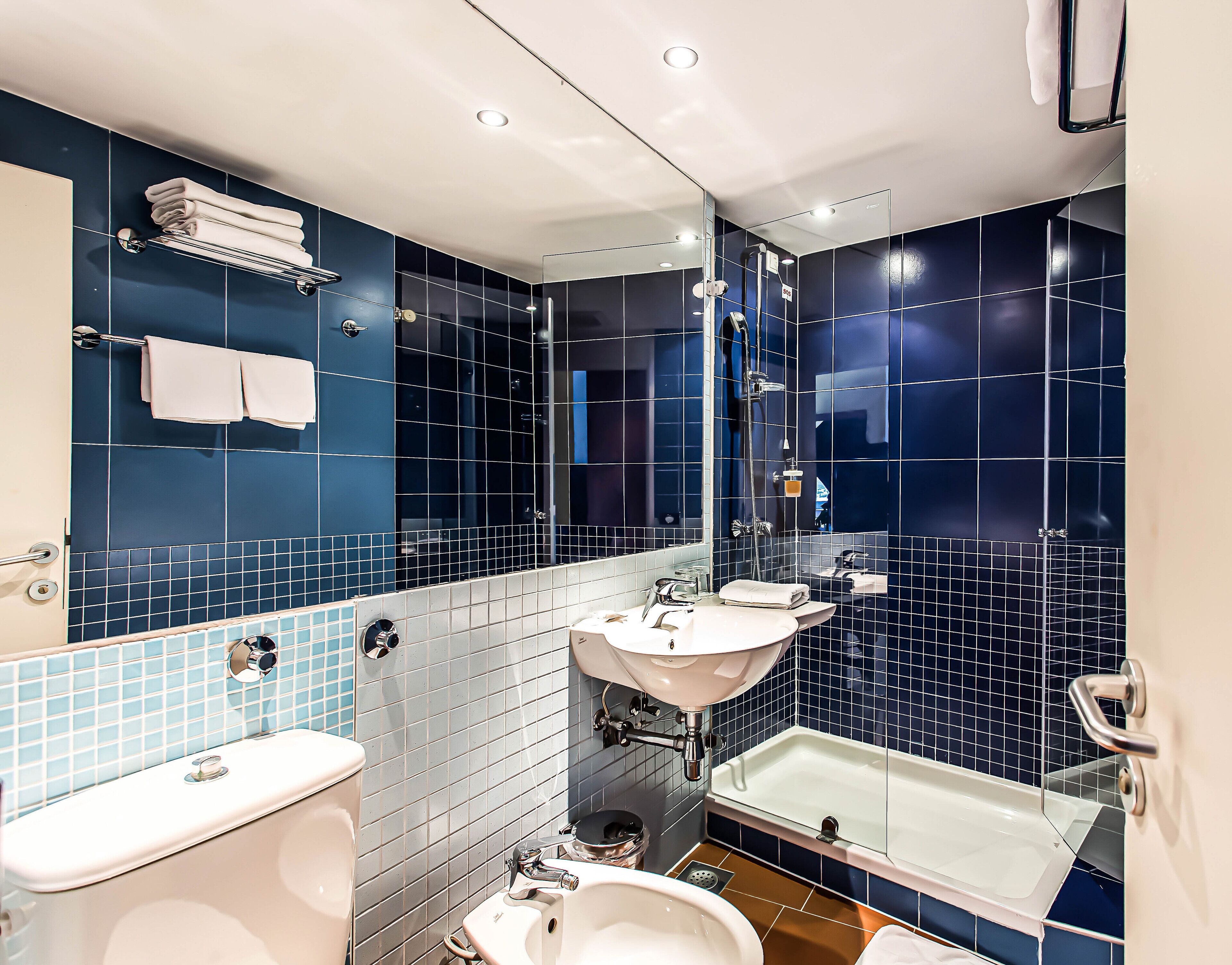 A modern bathroom with a bathtub, two sinks, and a toilet.