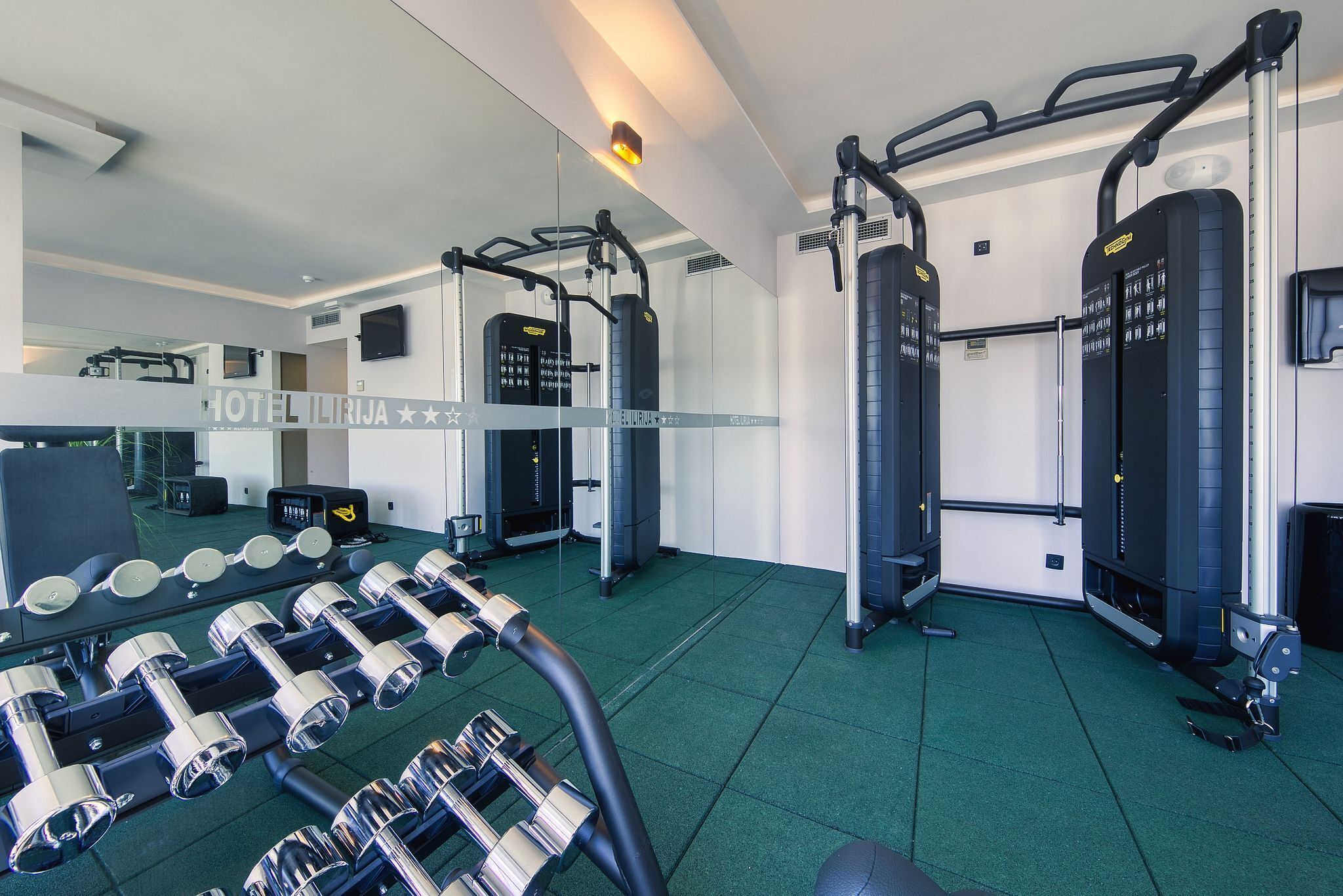 A hotel gym with weight machines, dumbbells, and a pull-up bar.