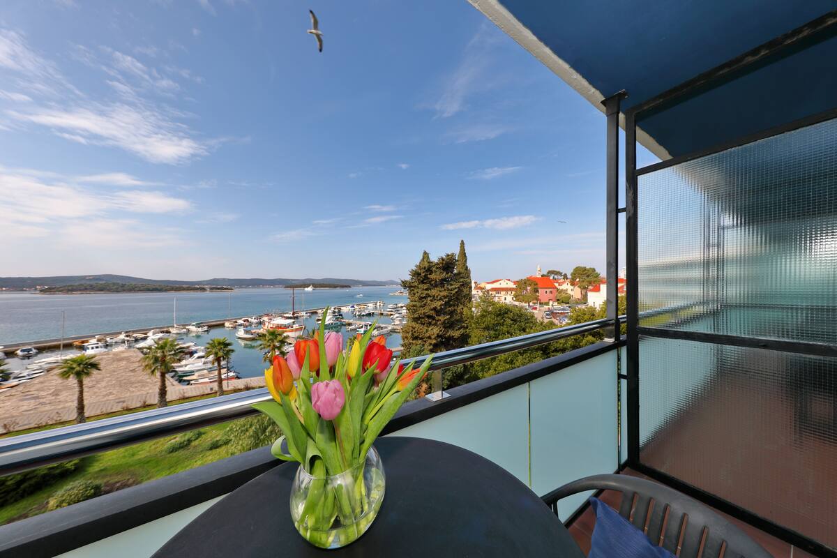 Un balcon avec vue sur un port de plaisance et la mer.