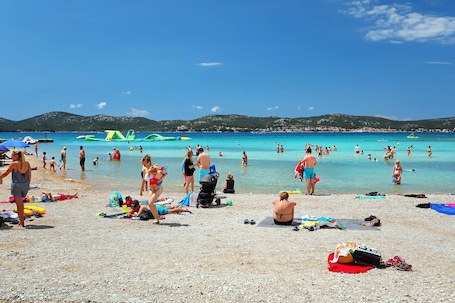 En la playa, arena blanca, sillas reclinables de playa, sombrillas