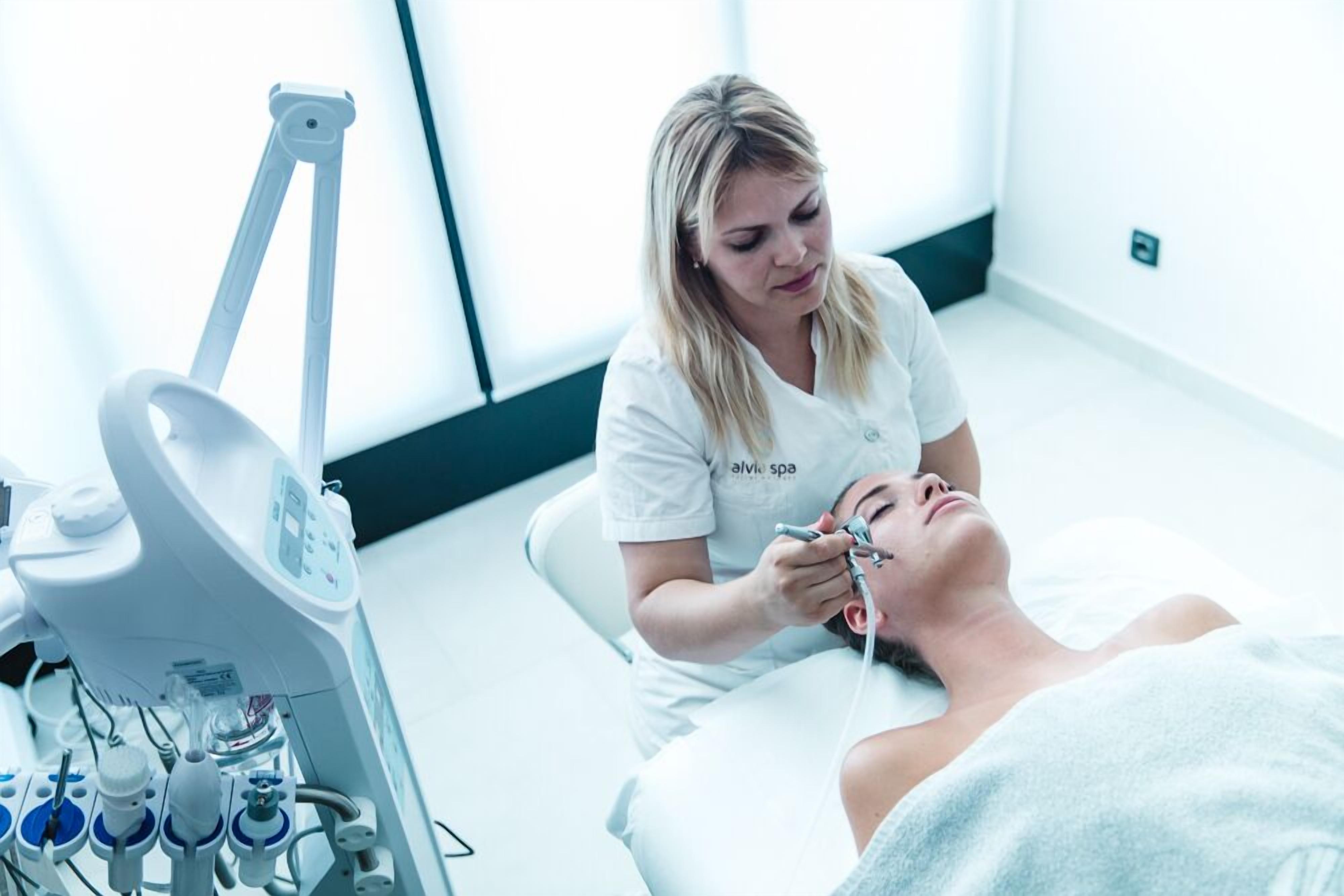 A medical procedure being performed in a clinical setting with a patient lying on a bed and a medical professional attending to them.