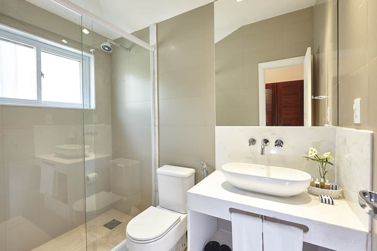 A modern bathroom with a glass-enclosed shower, a white sink, and a toilet.