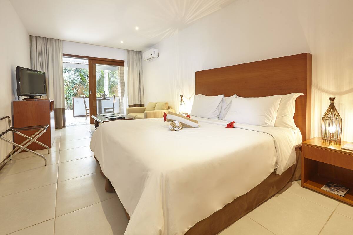 A hotel room with a large bed, a TV, a desk, and a chair.