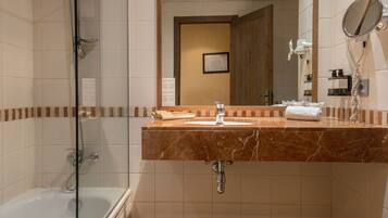 A bathroom with a marble sink, a glass shower enclosure, and a mirror with a hairdryer.