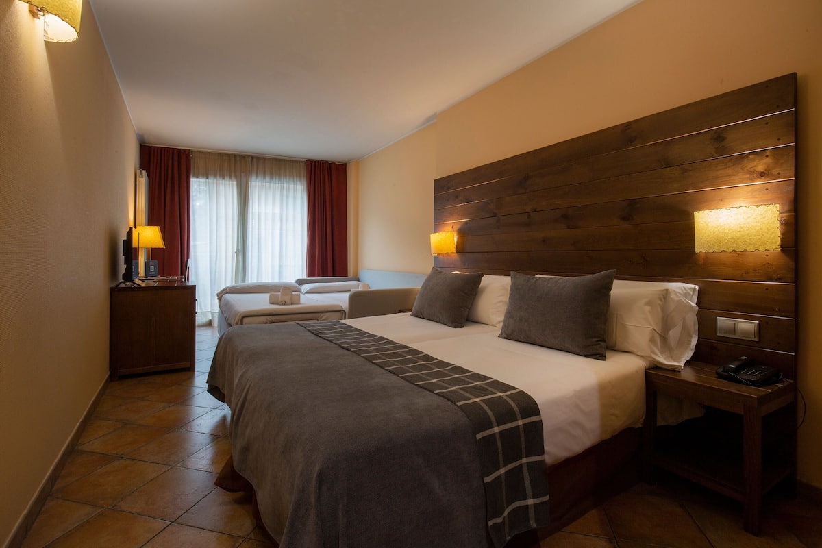 A hotel room with a large bed, two bedside tables, a nightstand, and a view of the room's interior.
