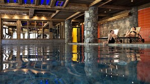 Una piscina interior con pilares de piedra, vigas de madera y vistas al área de la piscina.