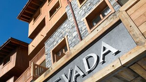 Un edificio con un letrero que dice "LE NEVADA" y detalles arquitectónicos de piedra y madera.