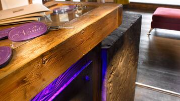Una reception in legno con piano in vetro, un portachiavi viola e una lampada sullo sfondo.