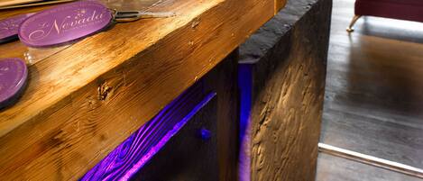 Un mostrador de recepción de madera con cubierta de vidrio, un llavero morado y una lámpara al fondo.