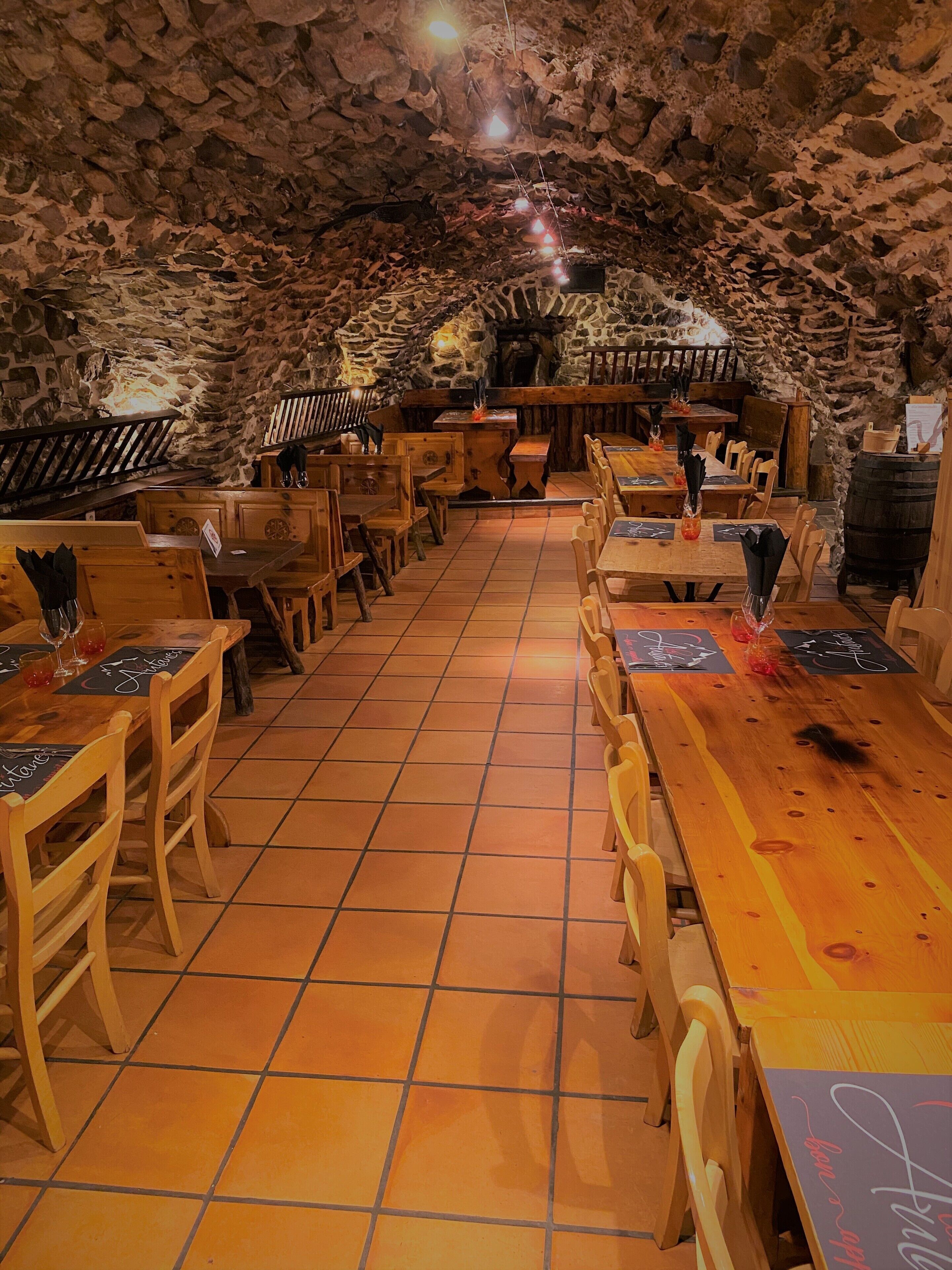 Un restaurant aux murs de pierre et aux tables et chaises en bois.