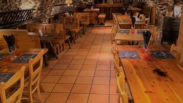 Un restaurant aux murs de pierre et aux tables et chaises en bois.