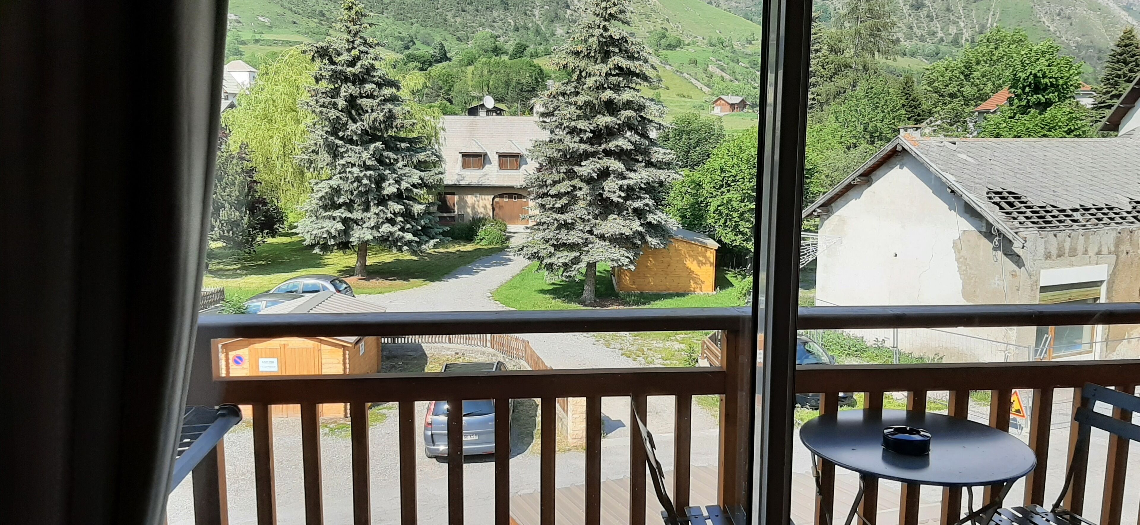 Un balcon donnant sur un paysage rural, avec des maisons et des arbres.