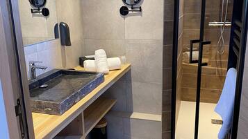A modern bathroom with a glass-enclosed shower, a marble sink, and a wooden vanity.