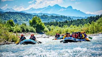 A group of people rafting on a river with mountains in the background.