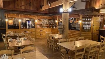 A rustic wooden interior with multiple dining tables and chairs, a coffee machine, and a display of kitchenware.