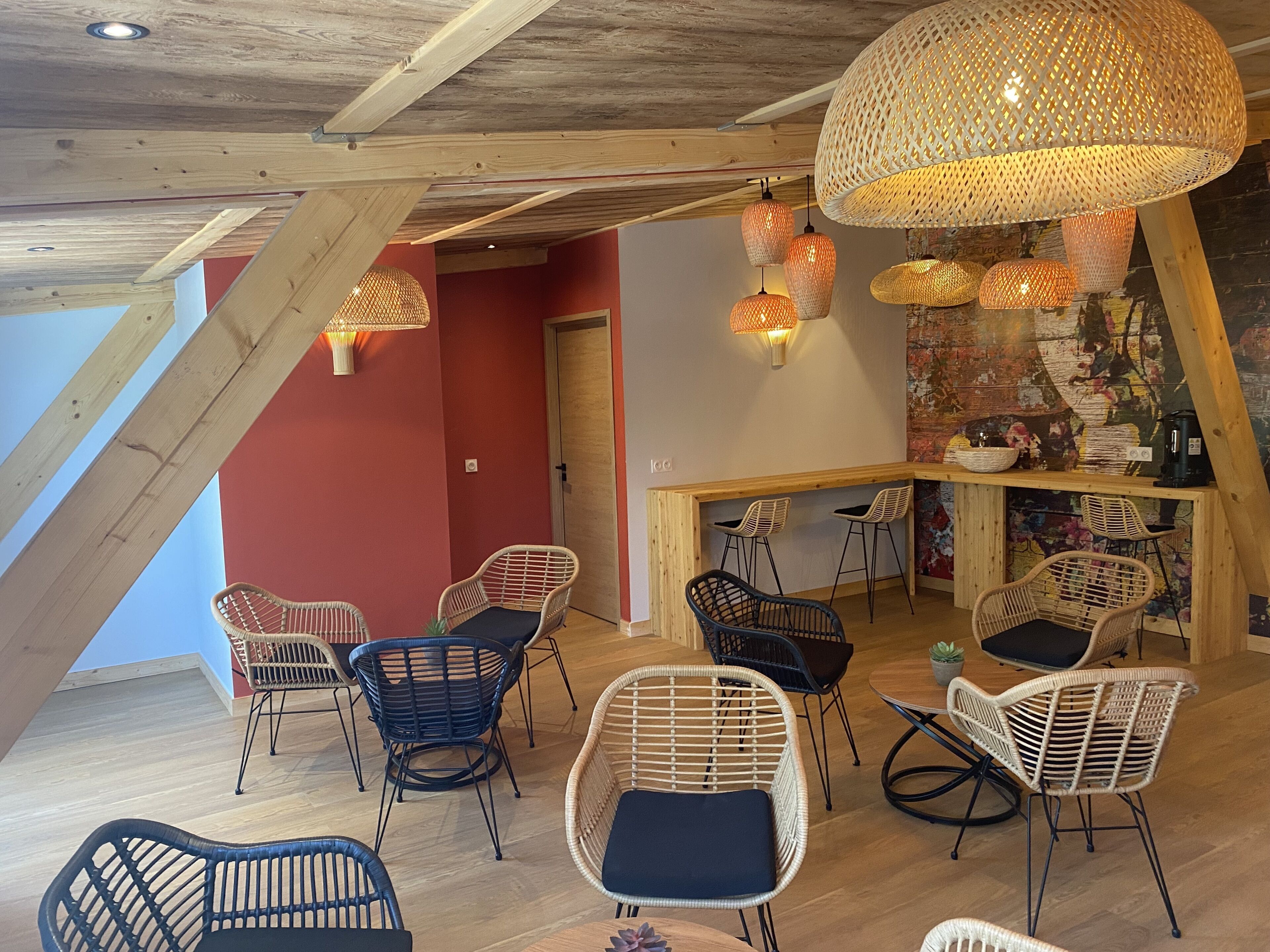 Un interno accogliente con travi in legno, poltrone in vimini e un'area bar con sgabelli.