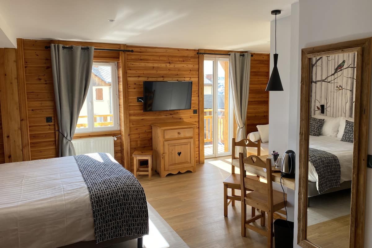 A wooden cabin bedroom with a bed, a TV, a small wooden cabinet, and a chair.