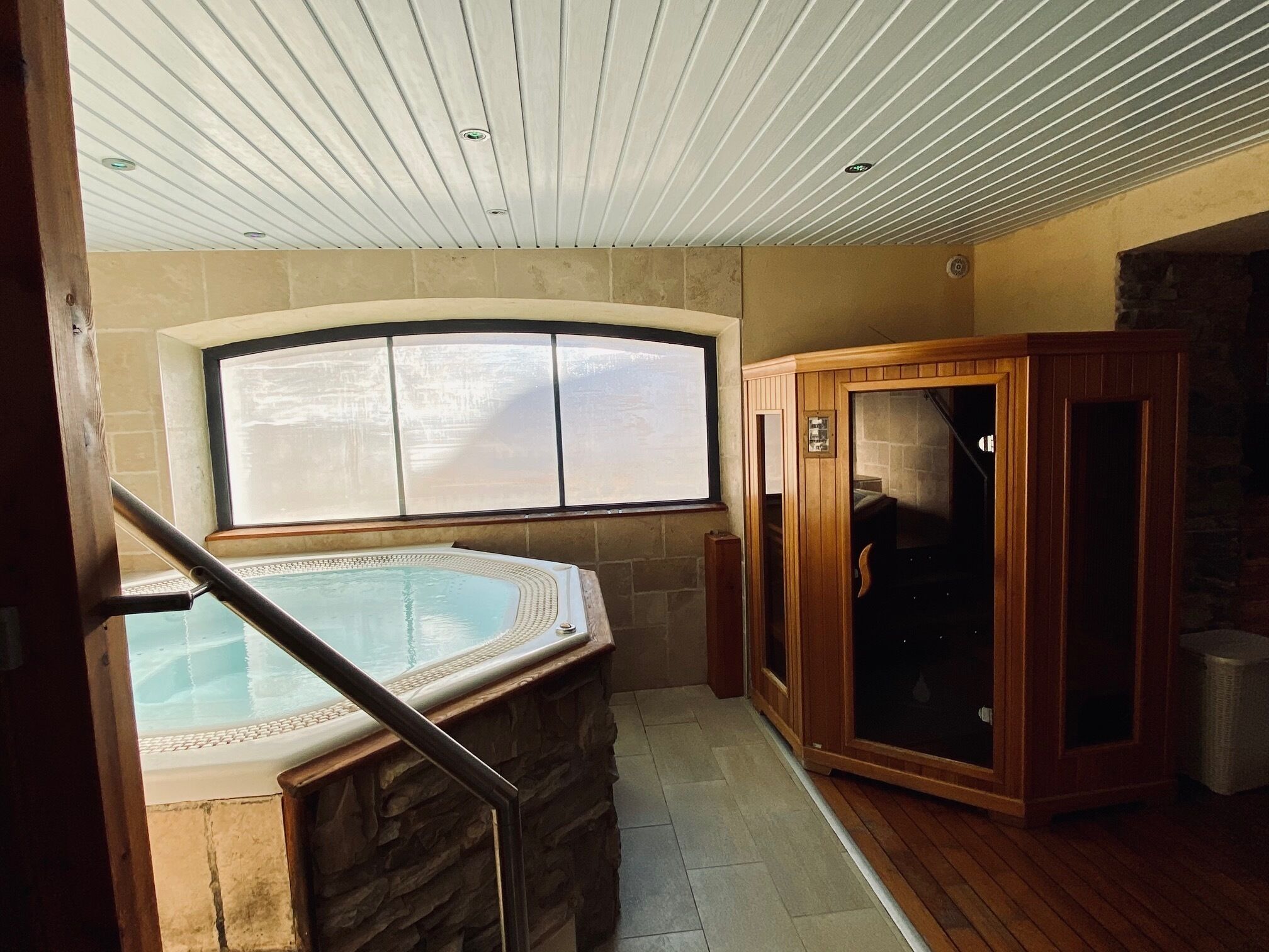 Un área de spa con jacuzzi, armarios de madera y una pared de piedra.