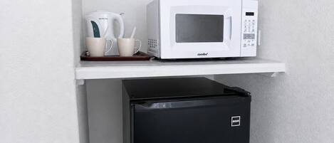 A compact kitchen setup with a microwave, a coffee maker, and a small refrigerator.