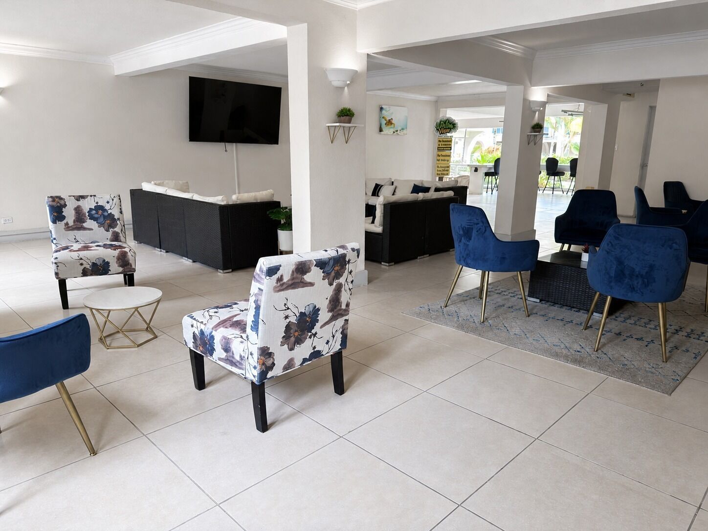 A modern living room with a flat-screen TV, floral-patterned chairs, and a blue sofa.