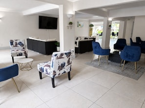 Una sala de estar moderna con un televisor de pantalla plana, sillas con estampado floral y un sofá azul.