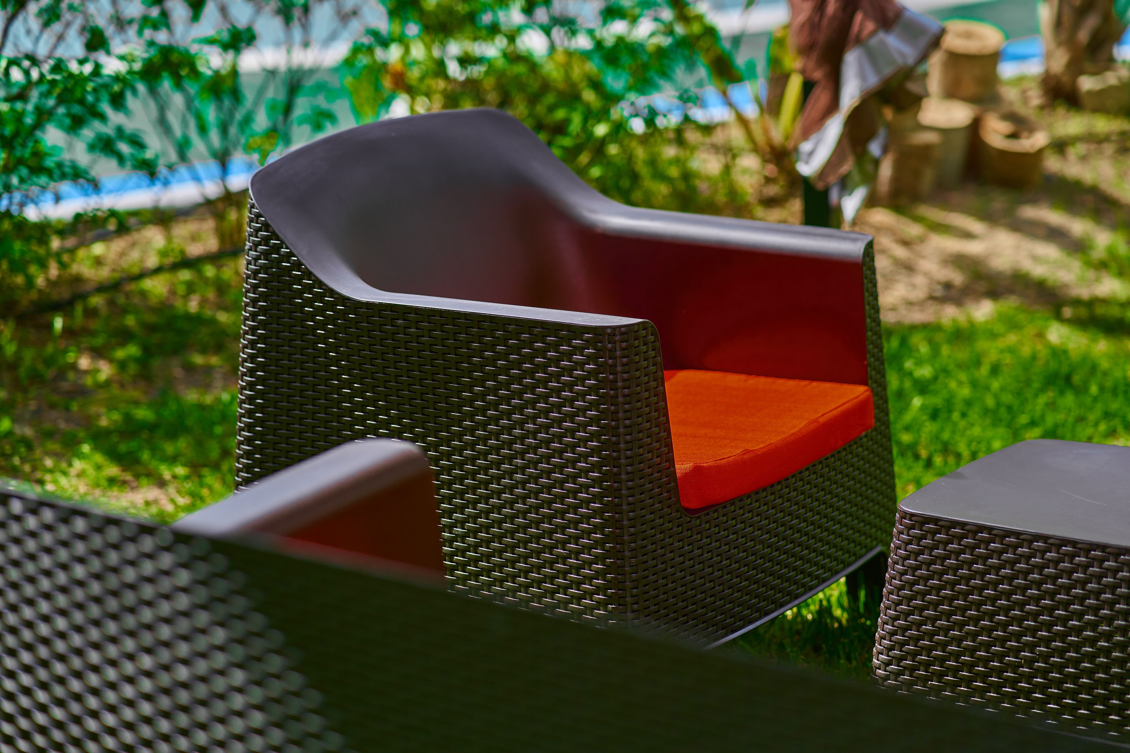 A wicker chair with a red cushion and a matching ottoman.