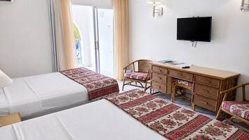Quarto de hotel com duas camas, uma escrivaninha, uma cadeira, televisão e janela com cortinas.