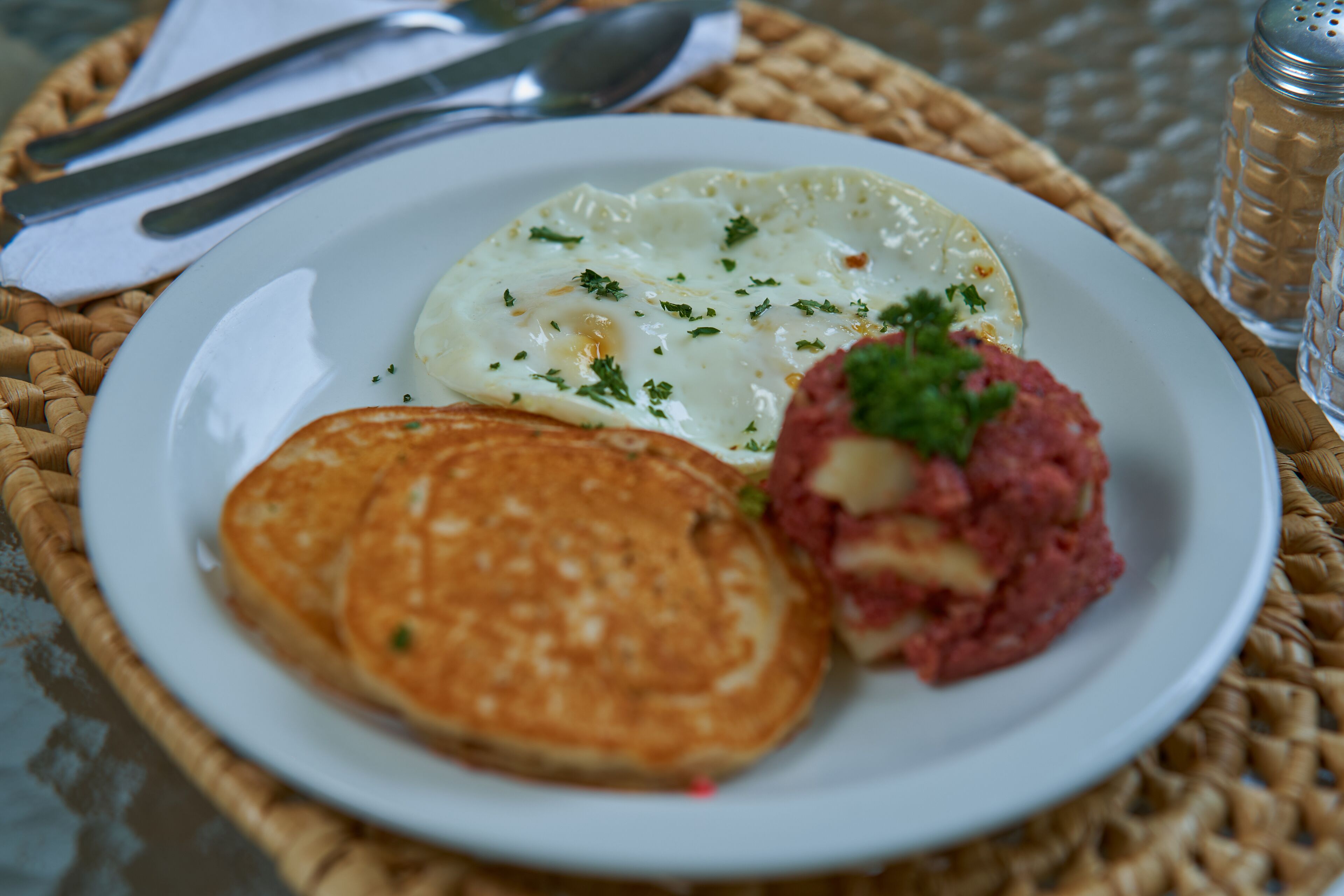 A plate with a fried egg, hash browns, and a meat patty.