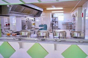 A kitchen with stainless steel appliances, a counter with food containers, and a green accent wall. - Sunbay Hotel (Maxwell)