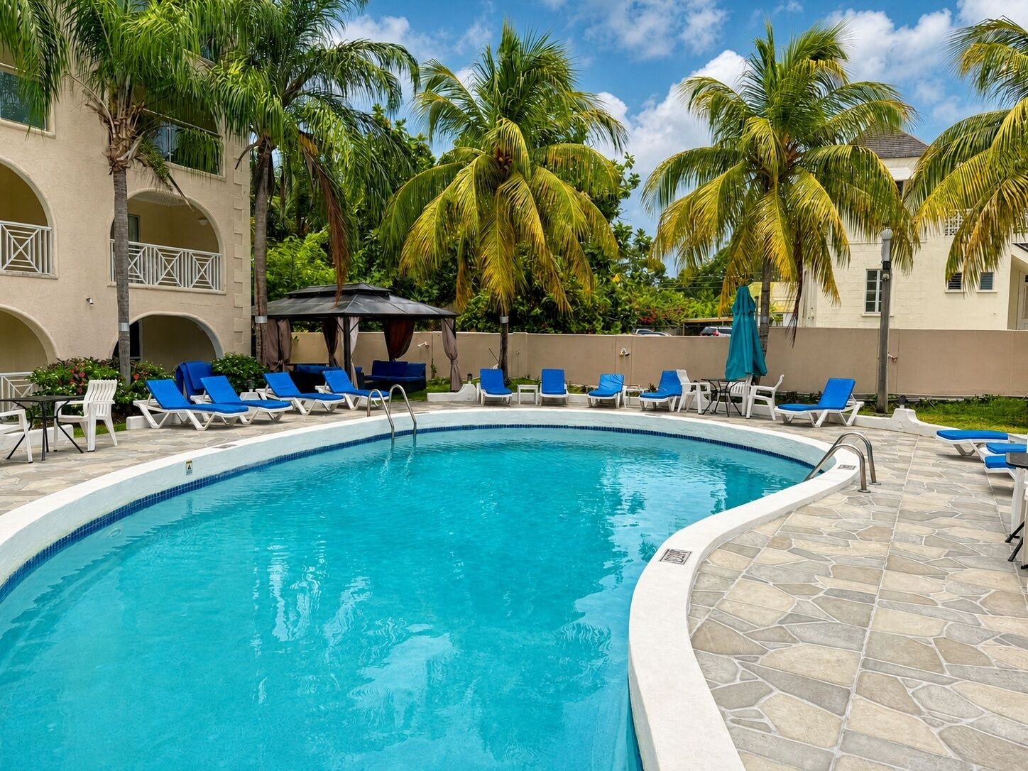 Une piscine bordée de chaises longues bleues et de palmiers.