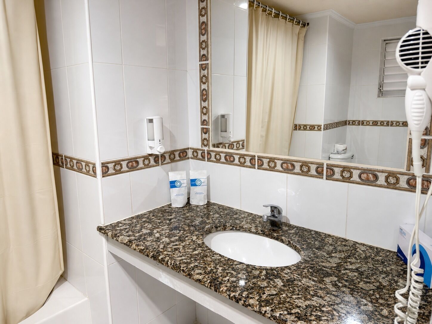 A bathroom with a white sink, a mirror, a towel rack, and a hairdryer.