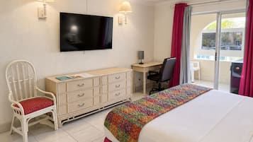 A hotel room with a bed, a desk, a chair, a television, and a window with curtains.